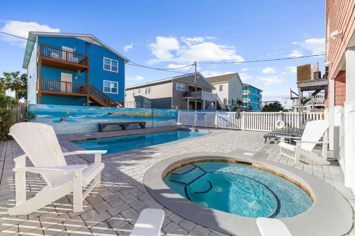 A lively backyard setting with a sparkling pool, hot tub, colorful mural, and deck chairs, capturing a sense of both relaxation and entertainment. The scene hints at memorable summer parties, peaceful mornings, and fun with family and friends.