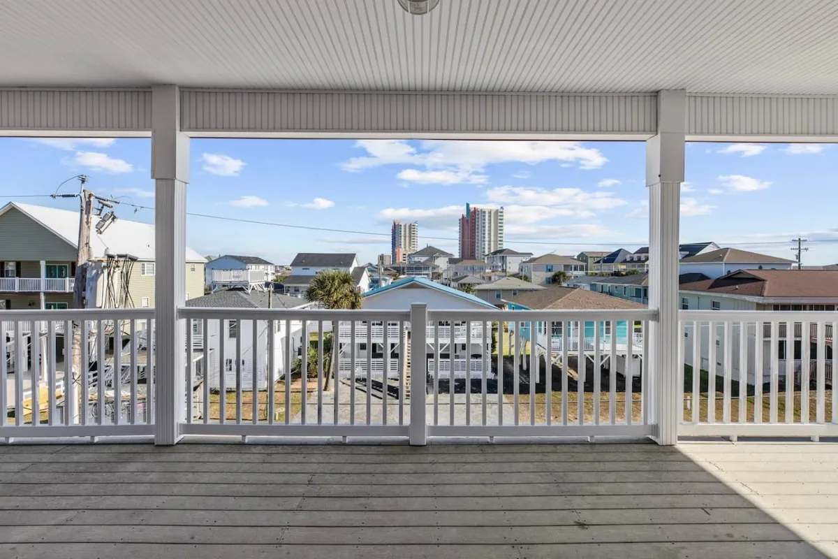 A tranquil balcony scene with a railing and a vista of nearby buildings and blue sky. The inviting space suggests a place to unwind, enjoy the breeze, or gather with friends after outdoor play.