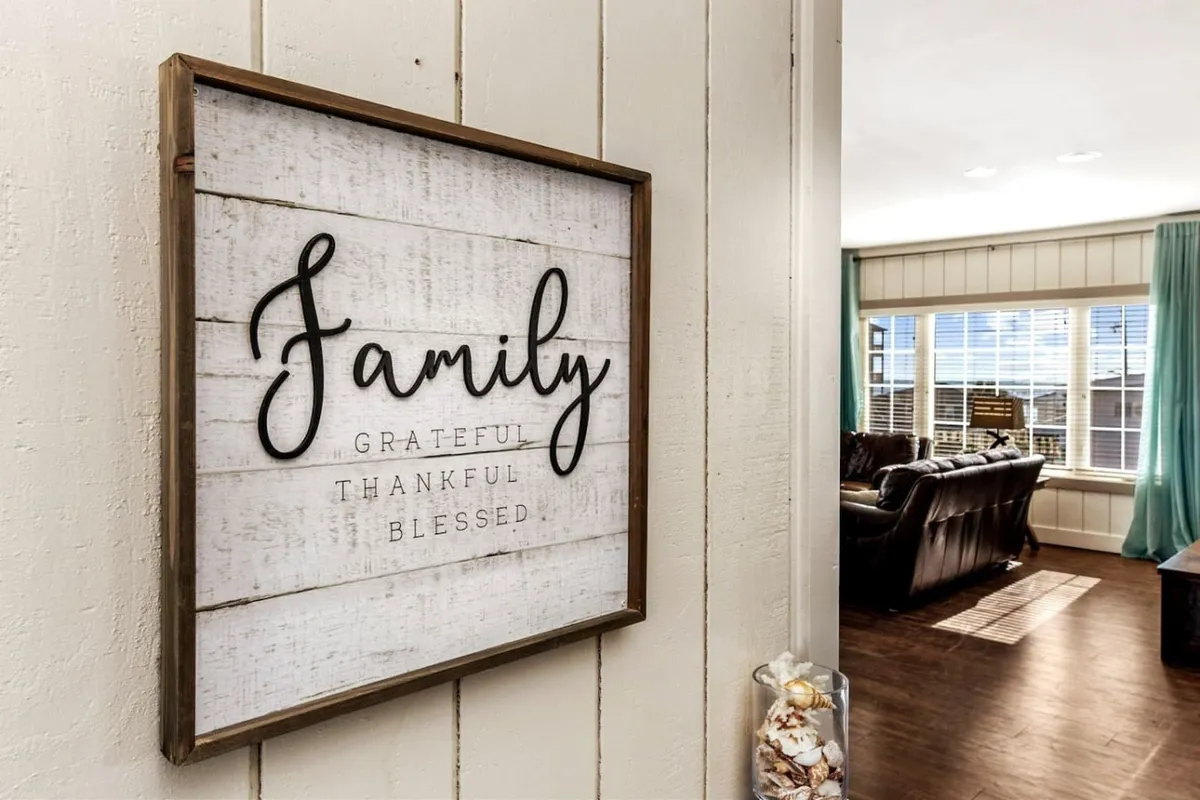 A welcoming living room with a 'Family' sign, large windows letting in ample light, comfortable seating, and a cozy ambiance. The arrangement encourages group relaxation, conversation, and shared experiences after a productive day.