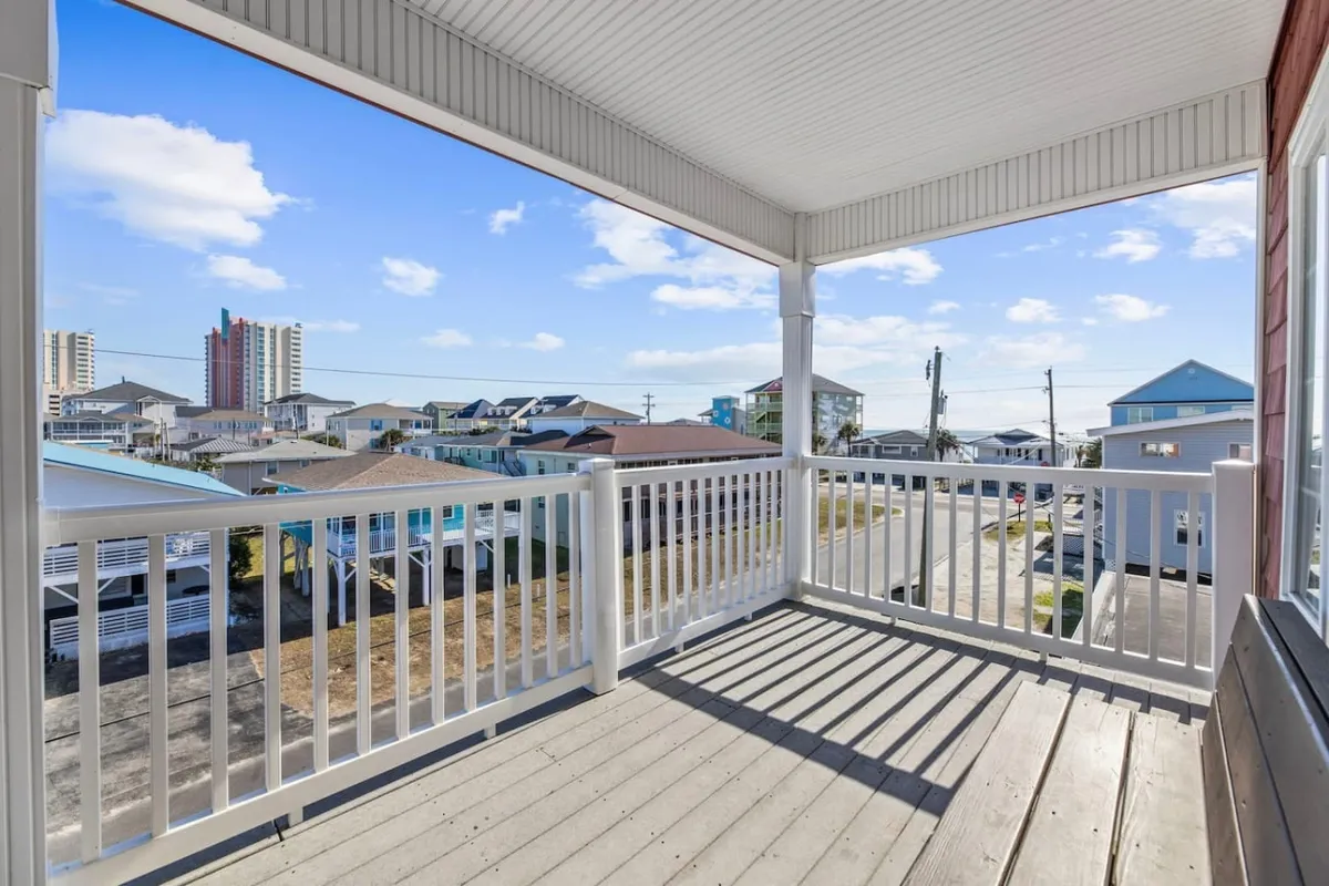 A balcony view overlooks surrounding homes in the Cherry Grove neighborhood, with a clear sky and distant skyline. The scene highlights the peacefulness of the residential area and the connection to outdoor spaces ideal for walks and relaxation.
